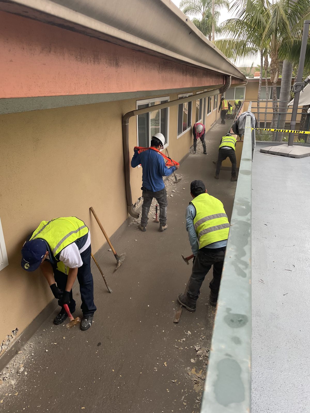 Crew chipping concrete on a commercial balcony walkway