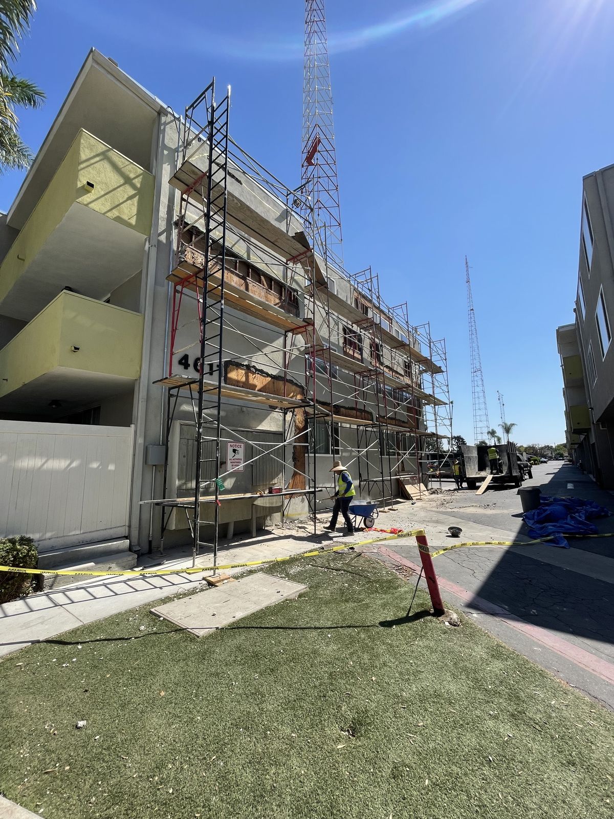 Commercial demolition crew on scaffolding along an apartment building exterior in San Diego