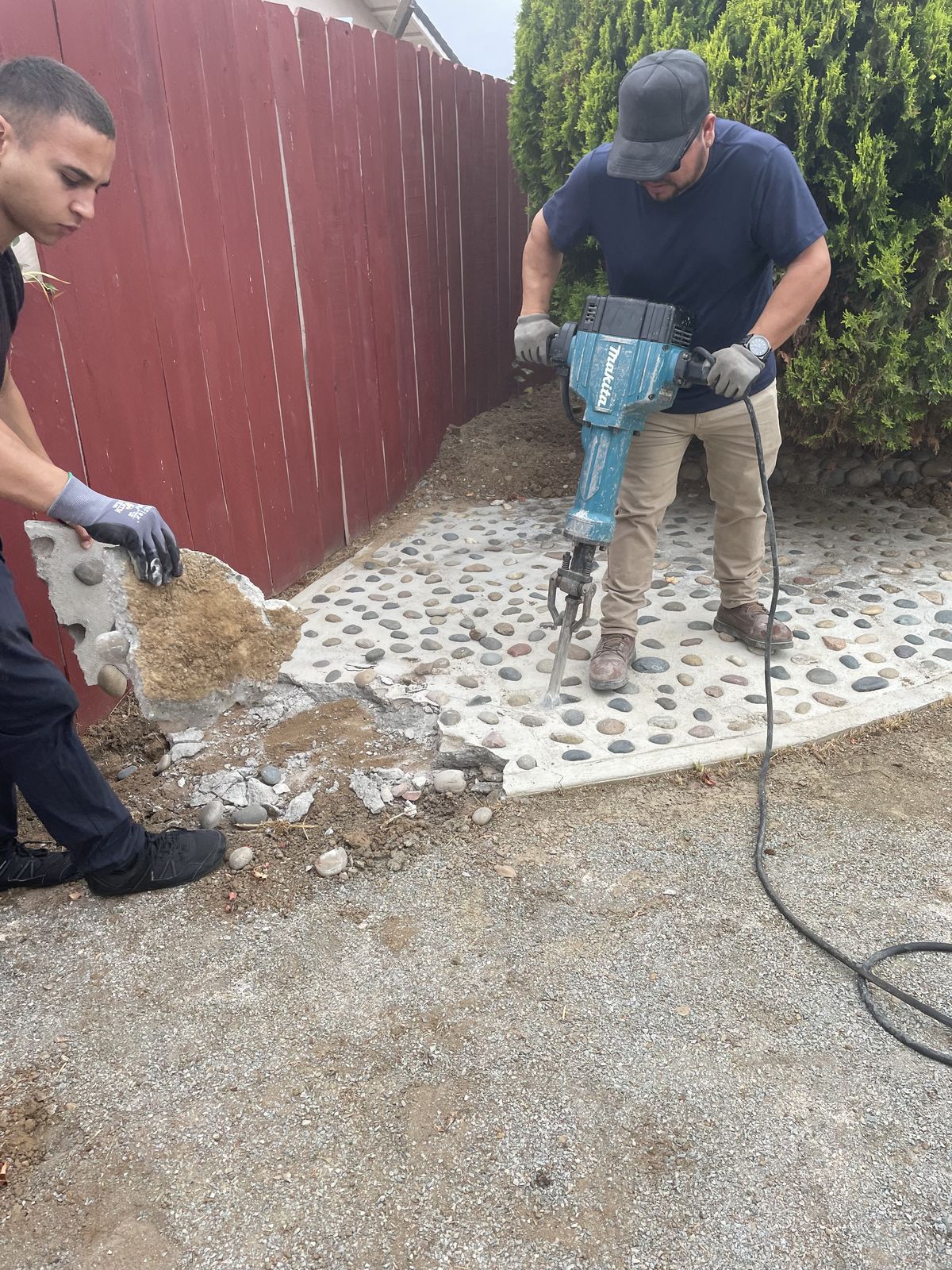 Worker breaking concrete with a Makita jackhammer during a concrete demolition job